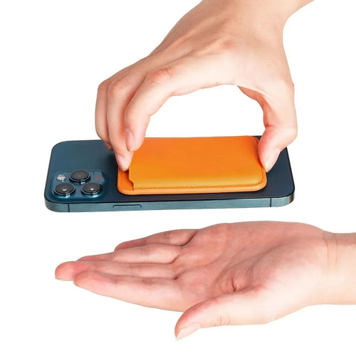 Hand attaching an orange magnetic phone wallet to the back of an iPhone